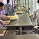 Line of students picking up plates of food handed off by cafeteria worker